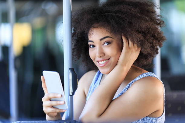 istock Smiling african woman with smart phone in a bus 825468768