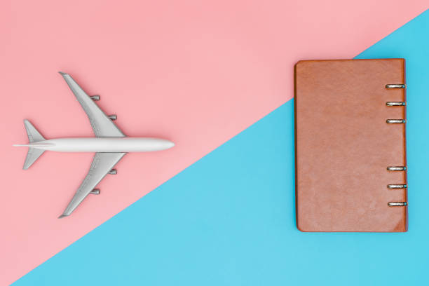 istock Toy plane and leather notebook on pink and blue copy space 825472090