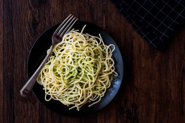 istock Spaghetti with pesto sauce on dark wooden surface. 825473362