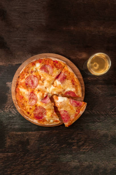 istock Pepperoni pizza with slice cut off, white wine, and copyspace 825477900