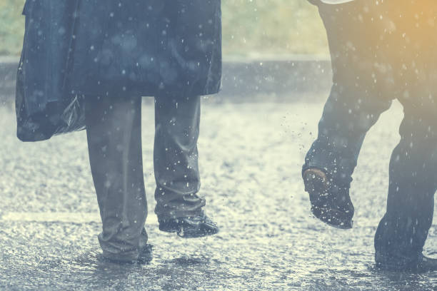 istock People running away through puddle at street during heavy rain. 825481724