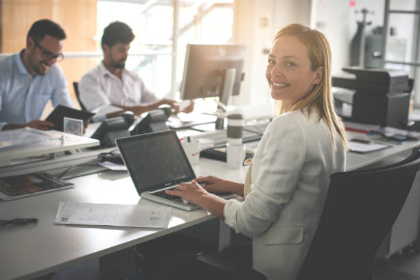 istock Business people in office. Woman using laptop and looking at camera. 825482570