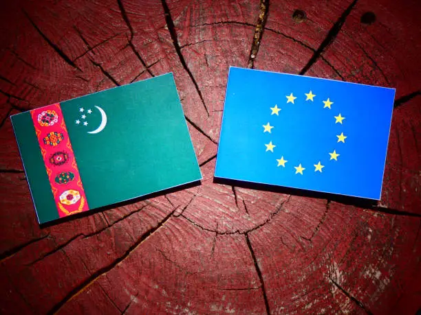 Photo of Turkmenistan flag with EU flag on a tree stump isolated