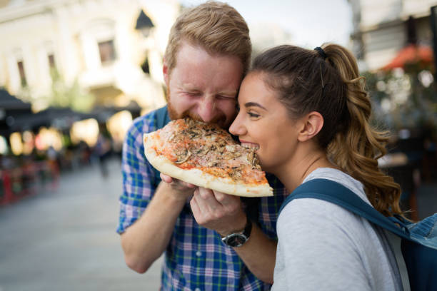 istock Happy couple sharing pizza on street 825522576