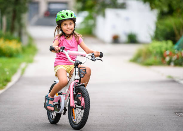 istock Children learning to drive a bicycle on a driveway outside. 825527010