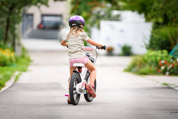 istock Children learning to drive a bicycle on a driveway outside. 825531068