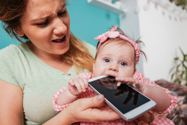 istock Baby girl biting smart phone 825534418