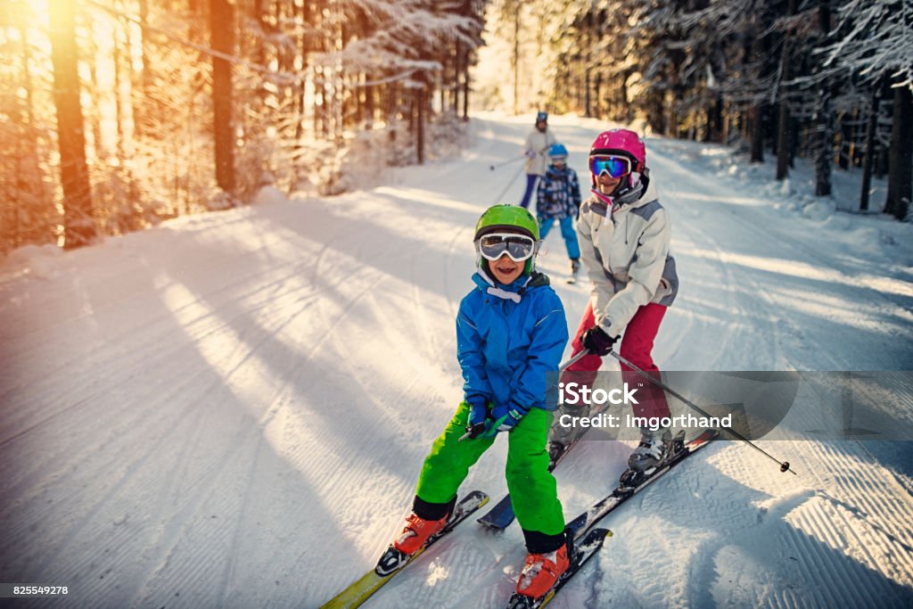 Family having fun skiing together on winter day Mother with kids are skiing together down the ski slope. Everybody is laughing happily. 

 Skiing Stock Photo