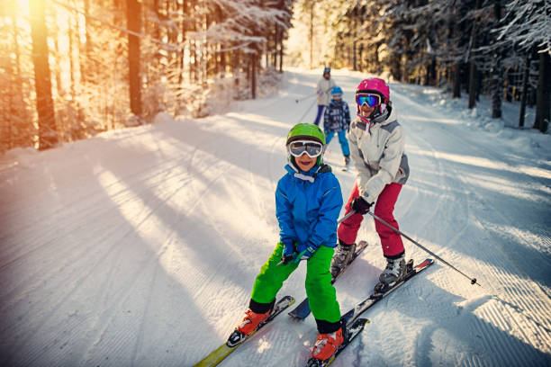 Family having fun skiing together on winter day Mother with kids are skiing together down the ski slope. Everybody is laughing happily. 

 crash helmet photos stock pictures, royalty-free photos & images