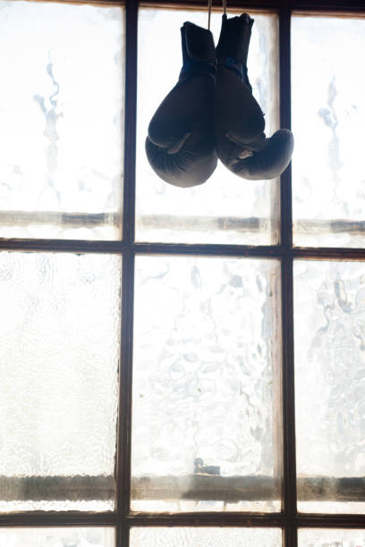 Pair of boxing gloves hanging on window in fitness studio