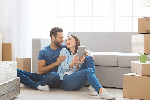 Young couple man and woman moving to a new apartment together relocation using digital device