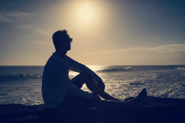 istock Modern man sitting on the beach and enjoying the view. 825565786