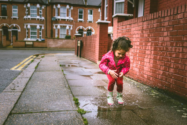 istock Child (5-6) in blue boots jumping in puddles. 825566340
