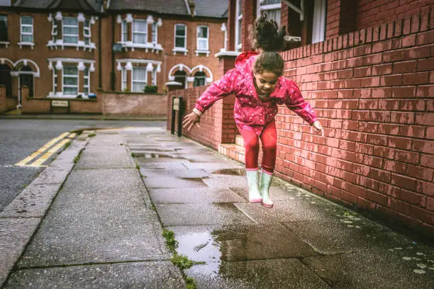 Stock photo of little girl who is having fun by jumping in puddles. This file has a signed model release.
