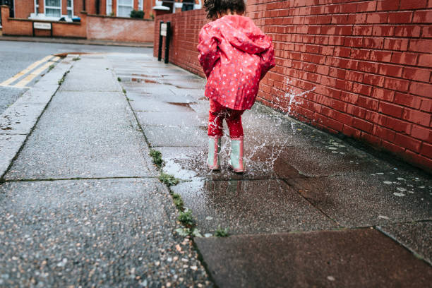istock Child (5-6) in blue boots jumping in puddles. 825566418