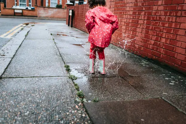 Stock photo of little girl who is having fun by jumping in puddles. This file has a signed model release.