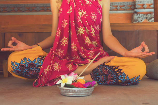 Woman practicing yoga with with canang sari - offering for Gods. Balinese tradition. stock photo