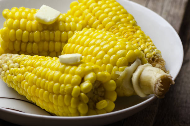 istock Boiled corn with piece of butter in white plate. 825573568