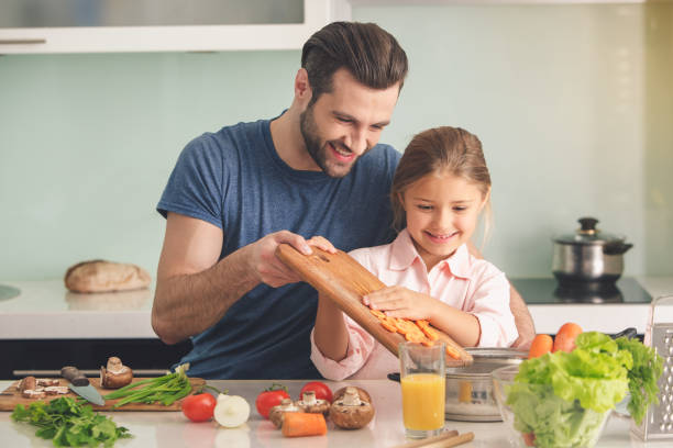 istock Young father and daughter cooking meal together 825574122