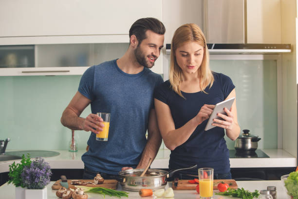 junges paar zusammen zu kochen, zubereitung von mahlzeiten indoor - standing digital tablet couple love stock-fotos und bilder