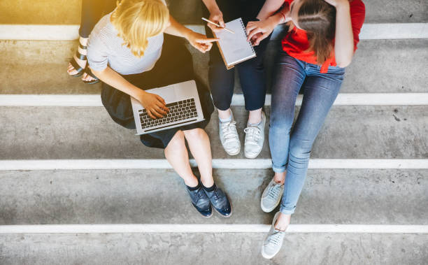 istock young and happy urban people sitting on steps with gadgets 825577054