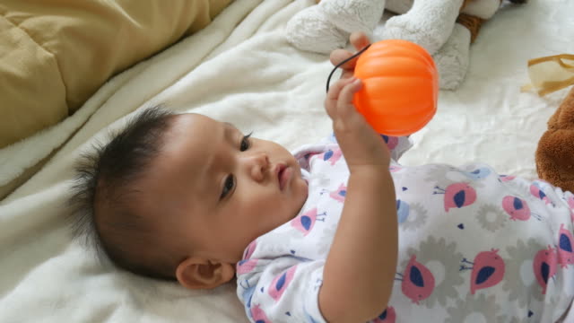 Asian baby smiling with pumpkin toy