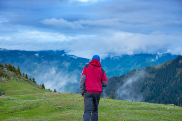 istock Traveler walks through the alpine meadow to the cliff 825580598