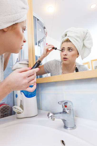 istock Woman in bathroom applying mascara on eyelashes 825583706