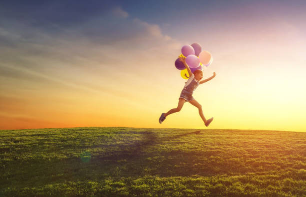 child is playing with balloons Happy little child is playing with balloons on meadow at sunset background. Kid is having fun and laughing on nature in the summer. happy day stock pictures, royalty-free photos & images