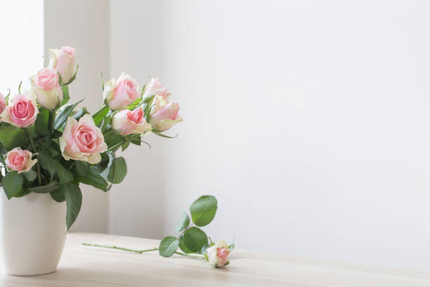 istock pink roses in vase on white background 825584904