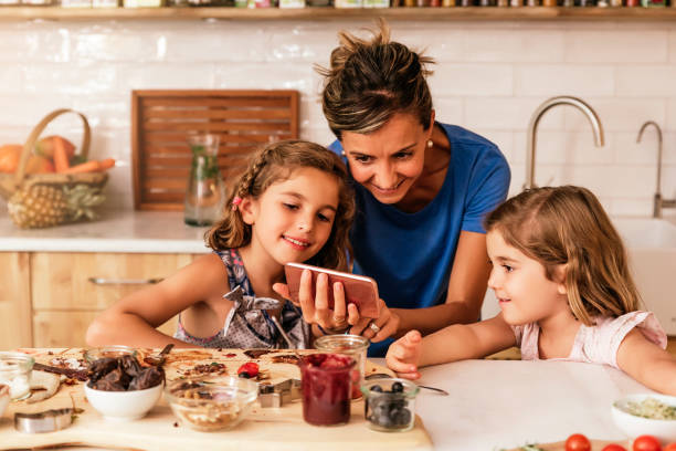 istock Little sisters cooking with her mother in the kitchen. 825593262