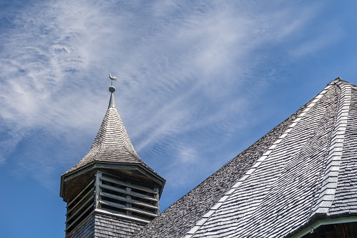 a close up view of the larch wood church in Obermutten with its wooden roof and shingles and wooden belfry