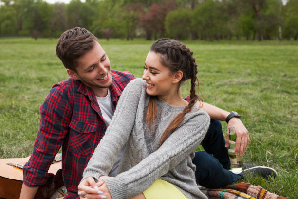 istock Smiling couple sitting on blanket in park. 825594210