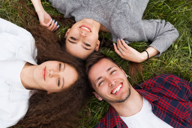 istock Two girls and guy lying on grass 825594386