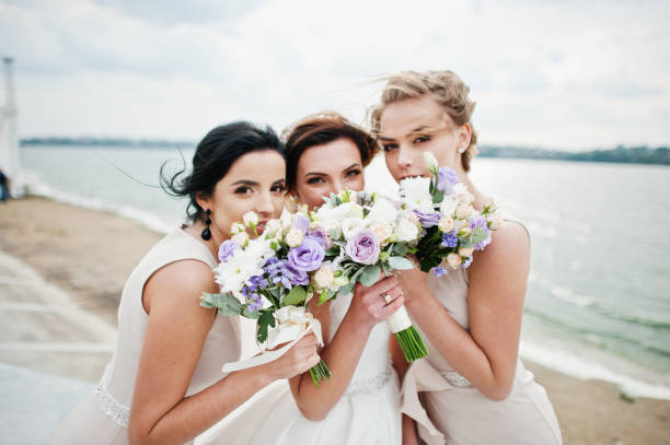 istock Stunning bride with pretty bridesmaids posing with bouquets on the lakeside. 825601220