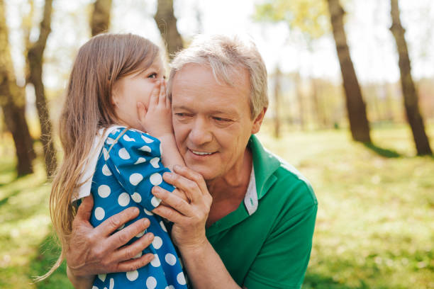 niña, contarle el secreto a abuelo - whispering grandparent child grandfather fotografías e imágenes de stock