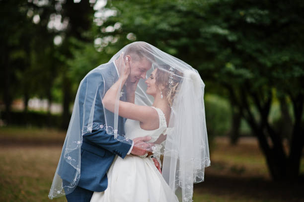 istock Wedding couple posing under bridal veil outdoor. 825608262