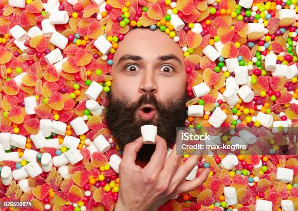 Bearded Guy Surrounded With Sweet Stuff Stock Photo - Download Image Now - Men, Bizarre, People