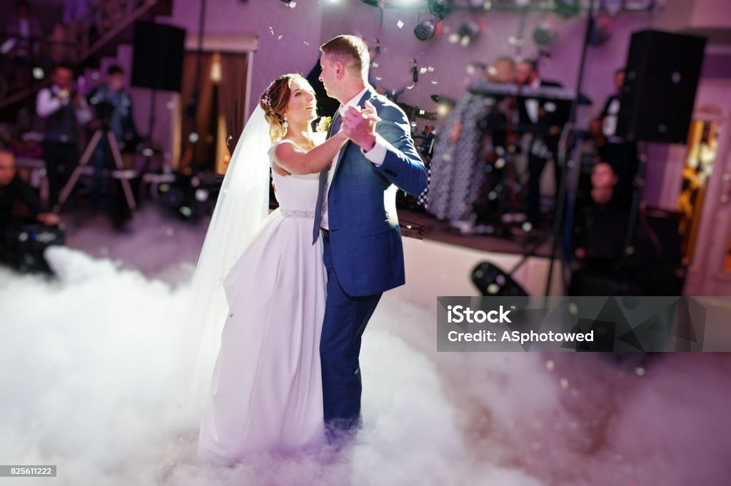 Świeżo poślubiona para tańczy na weselu z ciężkim dymem i wielobarwnymi światłami w tle. - Zbiór zdjęć royalty-free (Ślub)
