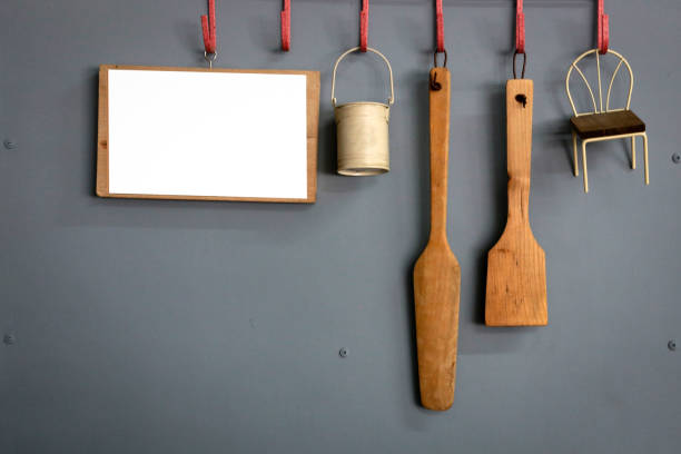 Equipment for cooking hanging on a gray wall with white board for writing.