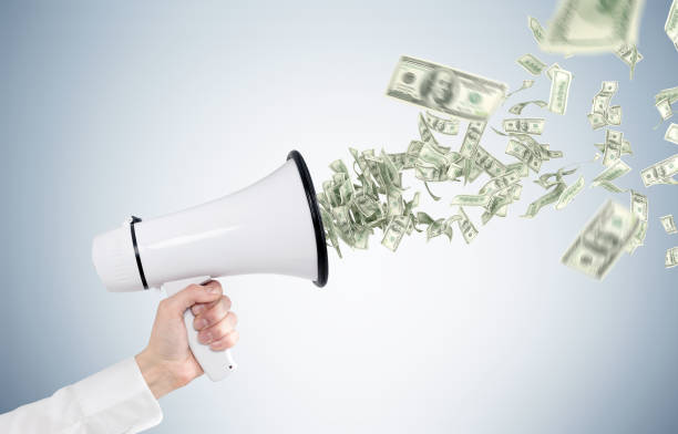 istock Man s hand holding megaphone, dollar bills 825620028