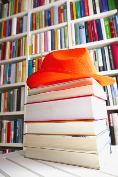 istock Stack of holiday books with an orange hat on top 825620670