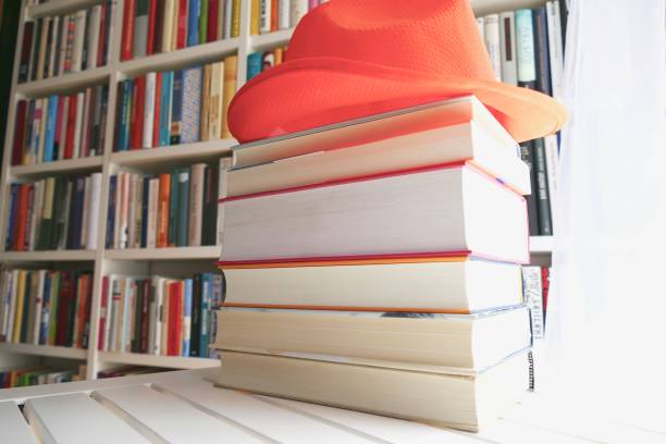 istock Stack of holiday books with an orange hat on top 825620736