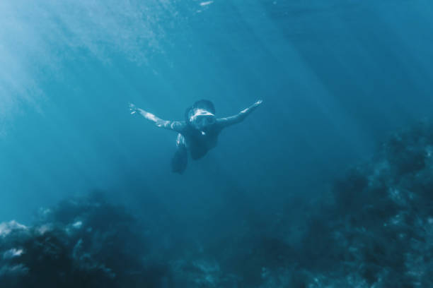 istock Female free diver swimming underwater. 825624120