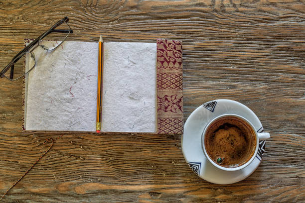 istock Open notebook with cup of coffee on old wooden table. 825630382