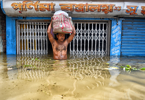 A businessman is carrying his cloth materials from his store to a safer place which is completely under water and make huge loss for him. Photo was taken at Howrah District on 28 July 2017 as the villages waterlogged due to excess water release by DVC.