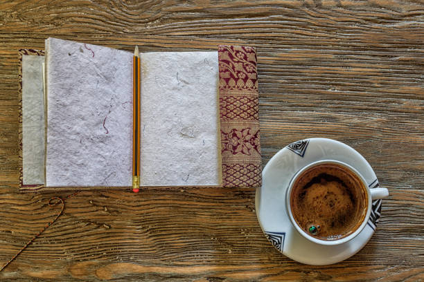 istock Open notebook with cup of coffee on old wooden table. 825635418