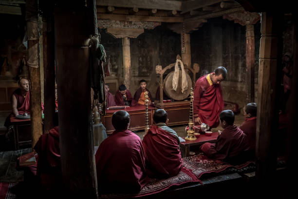 Red robed Buddhist novice monks having a tea break during their prayer in Lamayuru monastery in the Indian Himalaya. Lamayuru, Ladakh, India