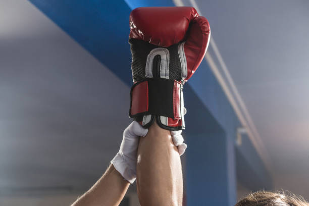 Referee holding hand of winning male boxer Referee holding hand of winning male boxer at fitness studio boxing referee stock pictures, royalty-free photos & images