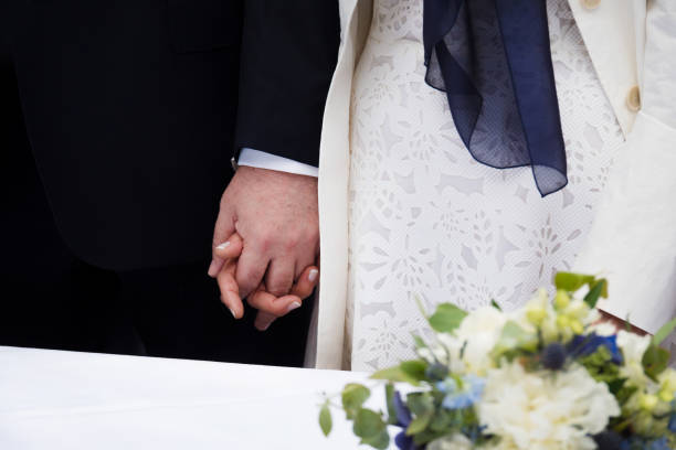 istock Bride and groom holding hands, flowers, late love 825654822